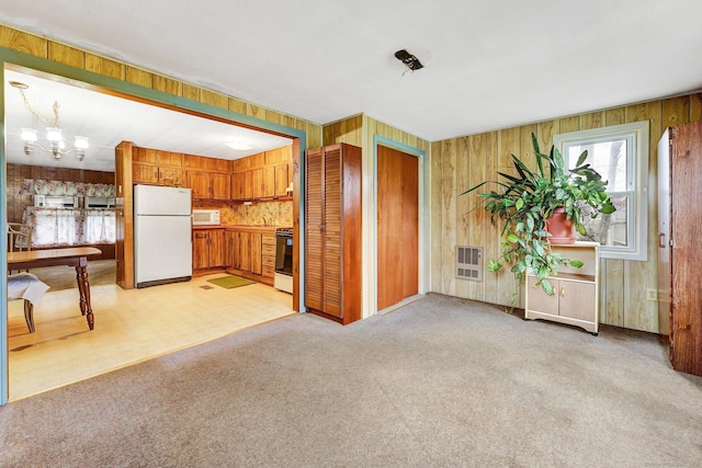 kitchen with heating unit, white appliances, a chandelier, and light carpet