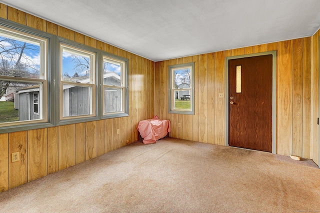 carpeted spare room featuring wood walls