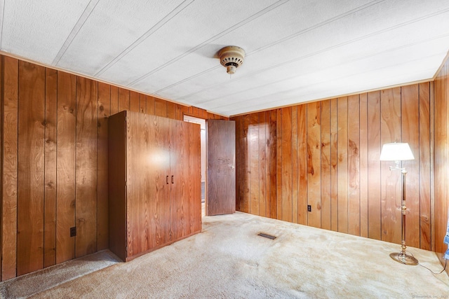 unfurnished room featuring carpet flooring and wood walls