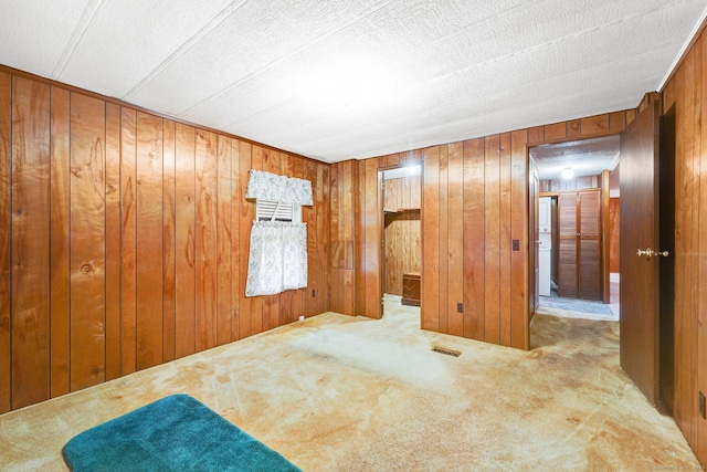 carpeted spare room featuring wood walls