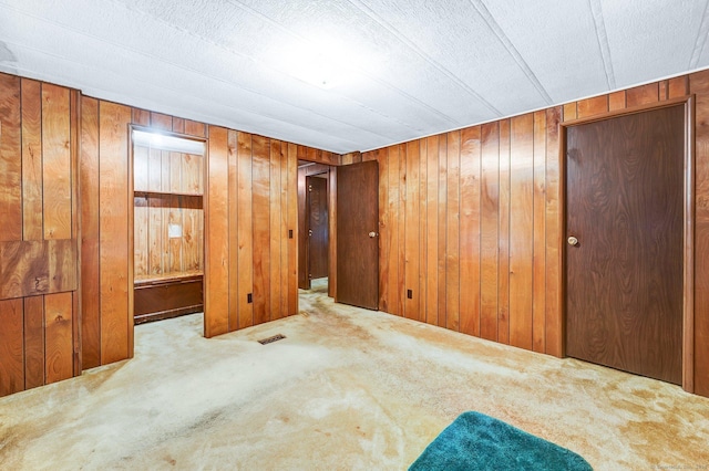 empty room with light carpet and wood walls