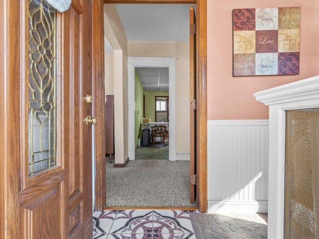 hall with carpet floors and wainscoting