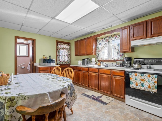 kitchen with range with electric stovetop, light countertops, a healthy amount of sunlight, a drop ceiling, and under cabinet range hood