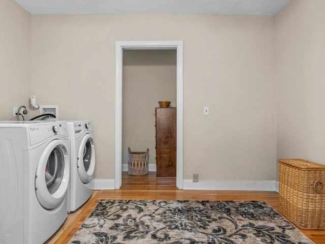 laundry room with laundry area, light wood finished floors, washing machine and clothes dryer, and baseboards