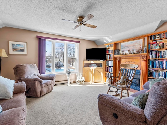 carpeted living area with a ceiling fan, a glass covered fireplace, lofted ceiling, a baseboard radiator, and a textured ceiling