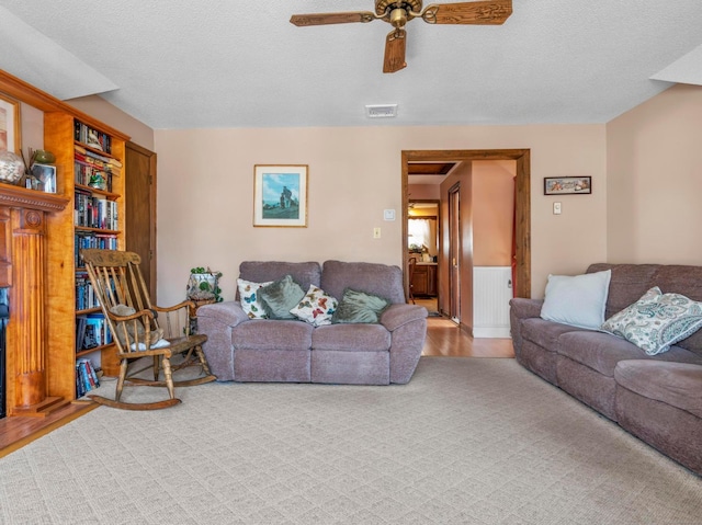 living room with ceiling fan, a textured ceiling, visible vents, and light wood-style floors