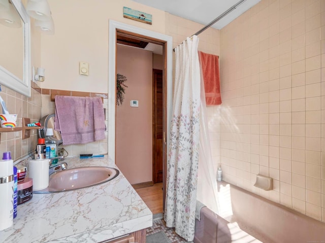 bathroom with backsplash, shower / tub combo with curtain, tile walls, and vanity