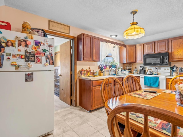 kitchen with pendant lighting, white appliances, light countertops, and brown cabinets