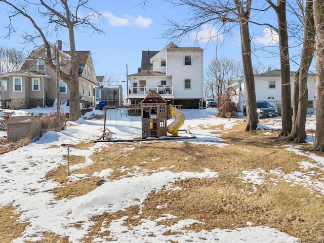 snow covered house with a residential view and a playground