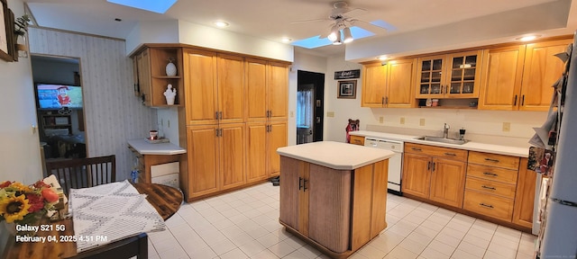 kitchen with sink, a skylight, white dishwasher, a kitchen island, and ceiling fan