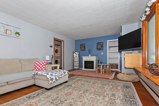 living room with stacked washer and dryer, dark wood-type flooring, and baseboard heating