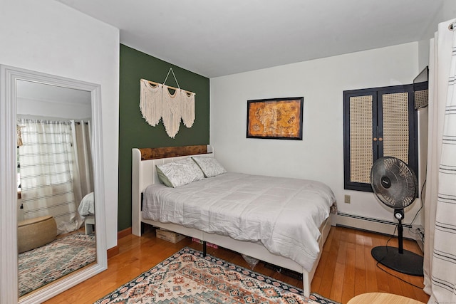 bedroom with wood-type flooring and a baseboard heating unit