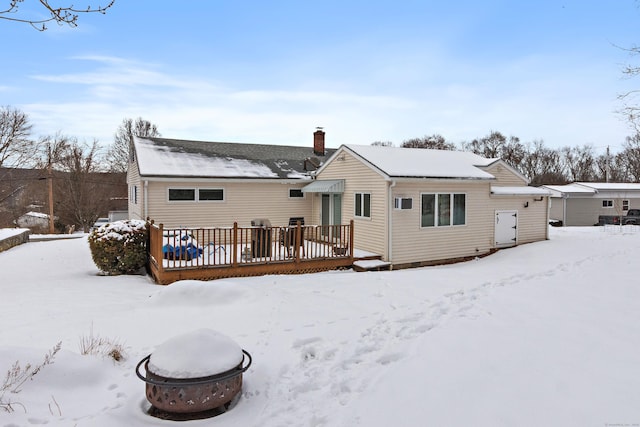 snow covered house featuring a deck and an outdoor fire pit