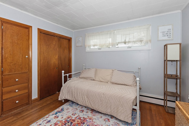 bedroom with crown molding, dark wood-type flooring, and baseboard heating