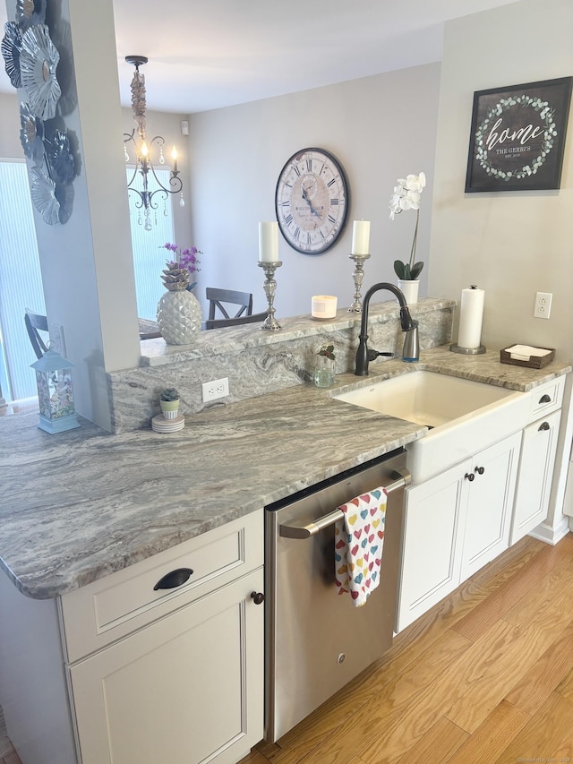 bar with decorative light fixtures, sink, white cabinets, stainless steel dishwasher, and light hardwood / wood-style floors