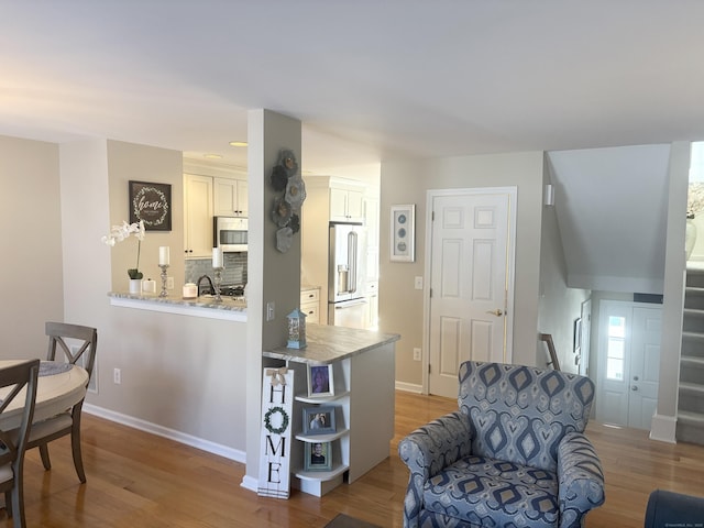 interior space with white cabinetry, hardwood / wood-style floors, tasteful backsplash, high quality fridge, and kitchen peninsula