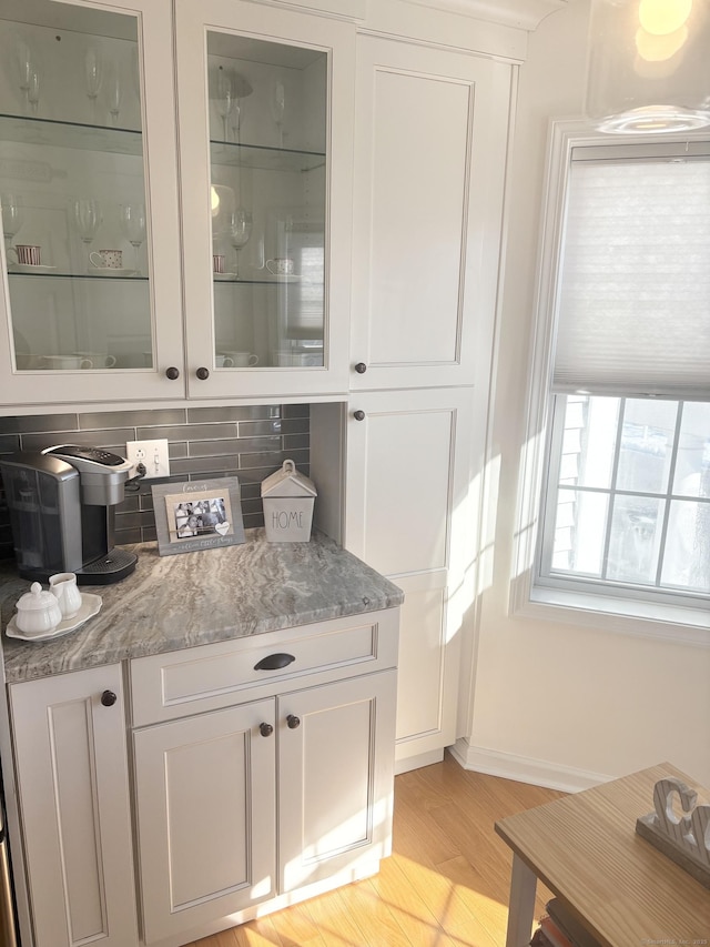 bar featuring white cabinetry, light stone countertops, light hardwood / wood-style floors, and decorative backsplash