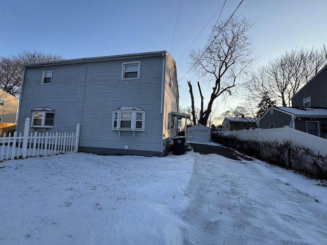 snow covered rear of property featuring an outbuilding and a garage