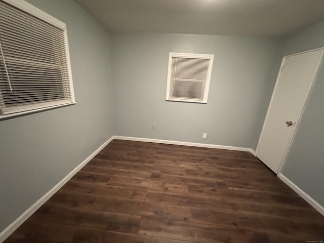 unfurnished room with dark wood-type flooring