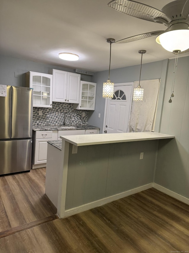 kitchen featuring white cabinetry, dark hardwood / wood-style floors, stainless steel fridge, and kitchen peninsula