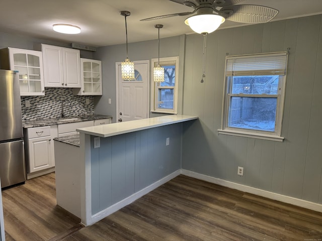 kitchen with stainless steel refrigerator, kitchen peninsula, sink, and white cabinets