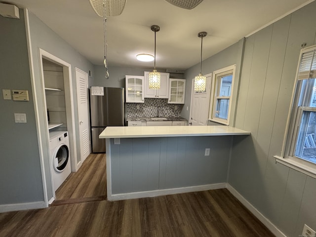 kitchen with white cabinetry, hanging light fixtures, stainless steel fridge, kitchen peninsula, and washer / clothes dryer