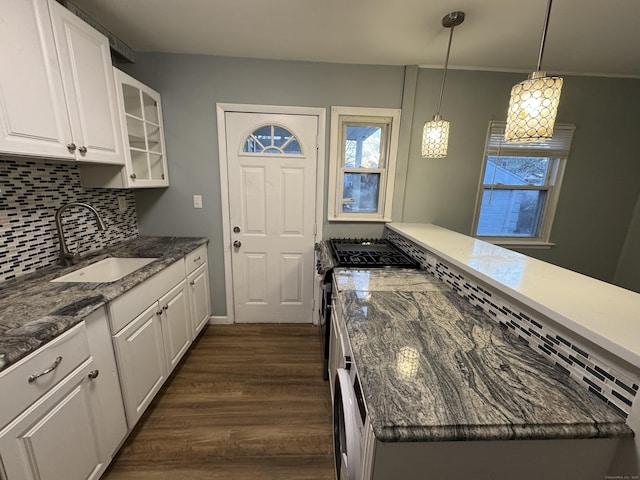 kitchen with pendant lighting, sink, white cabinets, dark stone counters, and gas range