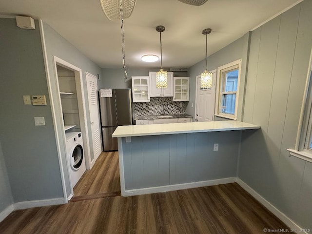 kitchen featuring washer / dryer, white cabinetry, hanging light fixtures, stainless steel fridge, and kitchen peninsula