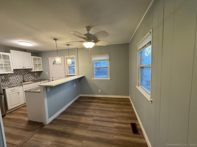 kitchen featuring pendant lighting, tasteful backsplash, white cabinetry, dark hardwood / wood-style flooring, and kitchen peninsula