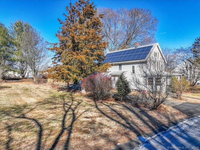 view of property exterior featuring a yard and solar panels