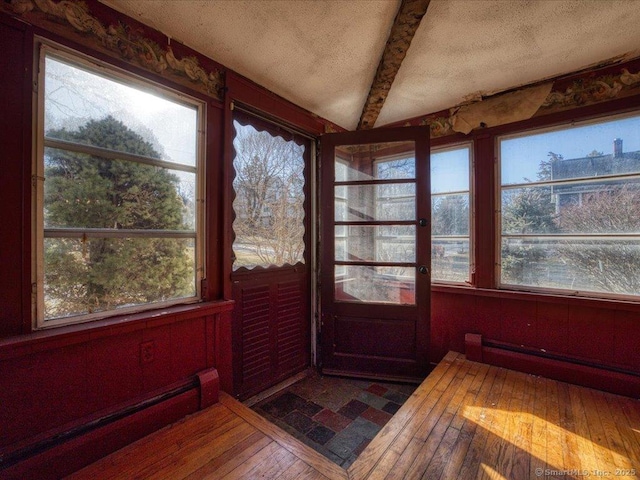 unfurnished sunroom with a baseboard radiator and beam ceiling