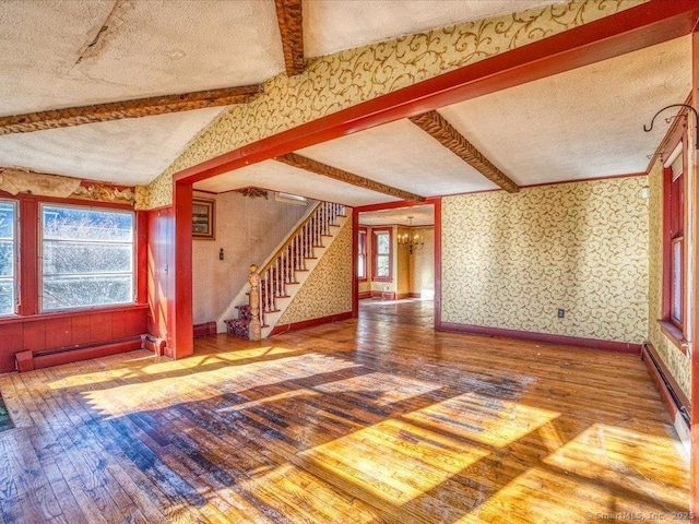 unfurnished living room with hardwood / wood-style floors, a wealth of natural light, lofted ceiling with beams, and baseboard heating