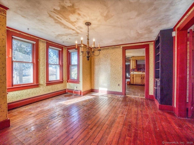 unfurnished dining area with wood-type flooring, sink, an inviting chandelier, and baseboard heating