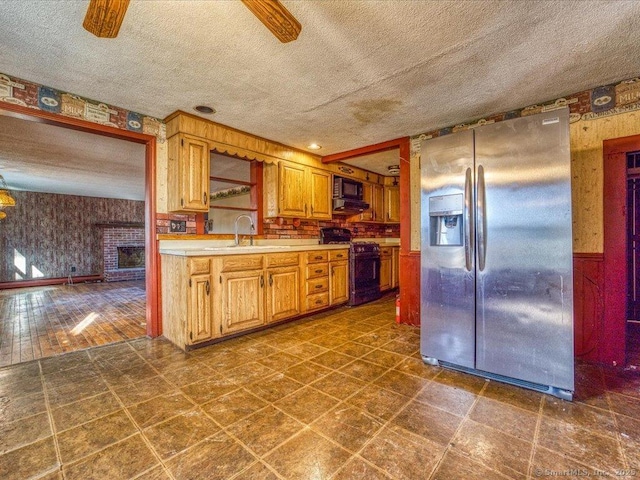 kitchen featuring sink, ceiling fan, a textured ceiling, stainless steel fridge with ice dispenser, and black range with gas stovetop