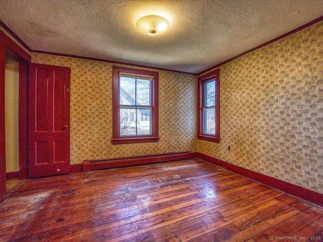 spare room with a baseboard heating unit, crown molding, a textured ceiling, and hardwood / wood-style flooring