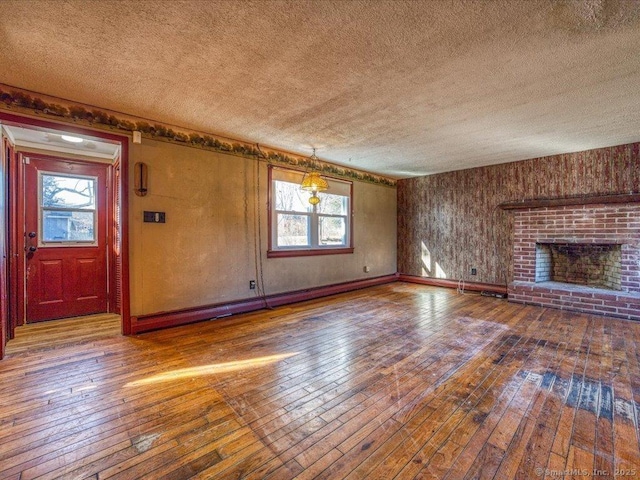 unfurnished living room with hardwood / wood-style flooring, a fireplace, and a textured ceiling