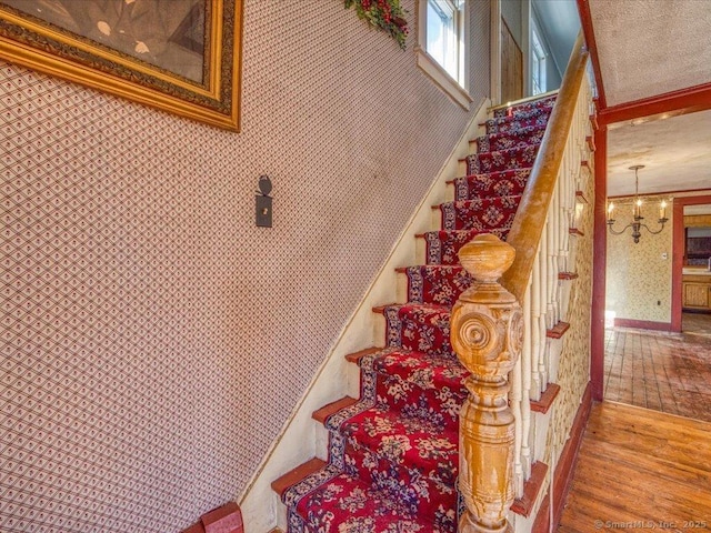 stairs with an inviting chandelier and wood-type flooring