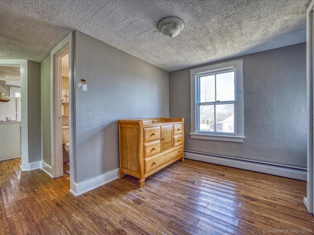 interior space featuring dark wood-type flooring, a textured ceiling, and baseboard heating