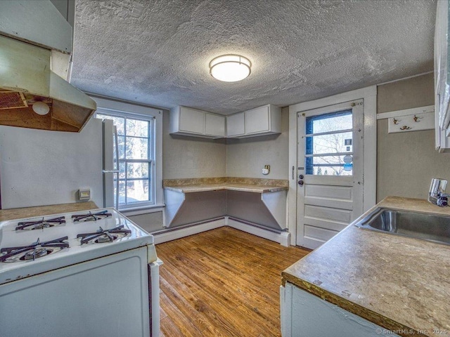 kitchen featuring white cabinetry, sink, light wood-type flooring, white appliances, and a textured ceiling