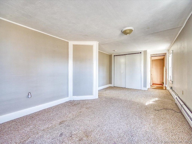 unfurnished bedroom featuring ornamental molding, carpet, baseboard heating, a textured ceiling, and a closet