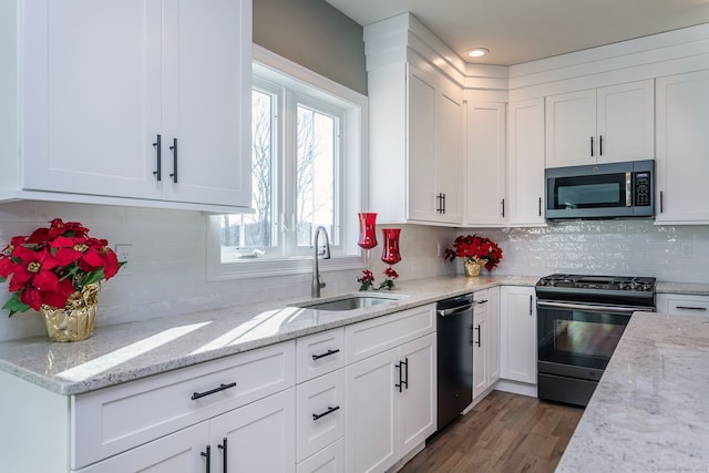 kitchen with white cabinetry, sink, decorative backsplash, light stone counters, and black appliances