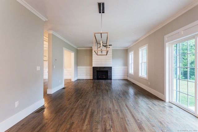 unfurnished living room featuring crown molding, a fireplace, dark hardwood / wood-style flooring, and an inviting chandelier