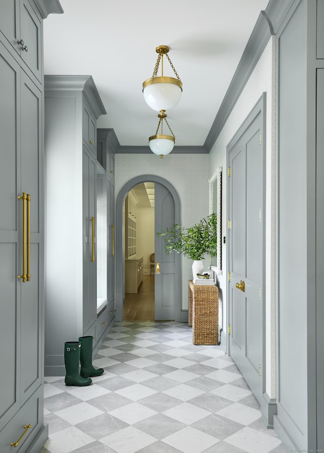 hall featuring light floors, arched walkways, and crown molding