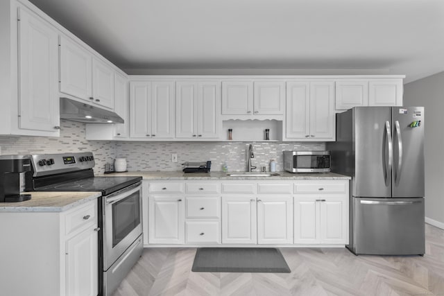 kitchen featuring appliances with stainless steel finishes, sink, white cabinets, decorative backsplash, and light stone countertops