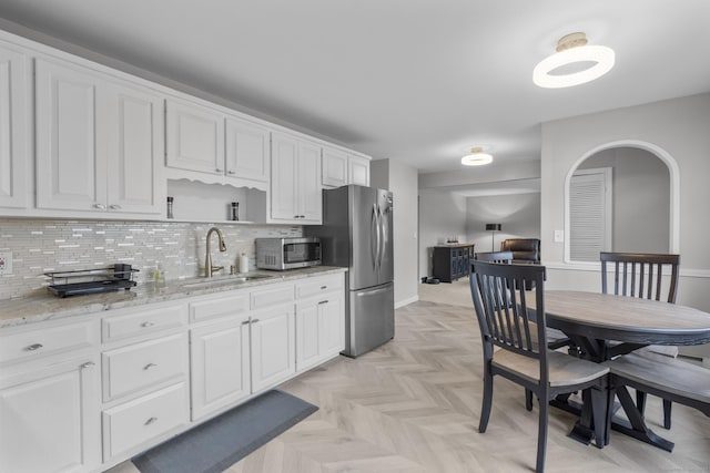 kitchen featuring stainless steel appliances, light stone countertops, sink, and white cabinets