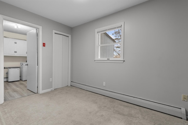 unfurnished bedroom featuring ensuite bathroom, a baseboard heating unit, light colored carpet, and a closet