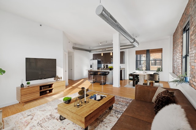 living room with rail lighting, brick wall, and hardwood / wood-style floors