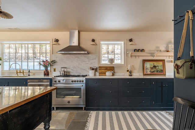 kitchen featuring a wealth of natural light, tasteful backsplash, sink, stainless steel appliances, and wall chimney range hood