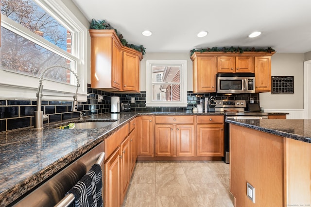 kitchen with stainless steel appliances, decorative backsplash, and a wealth of natural light