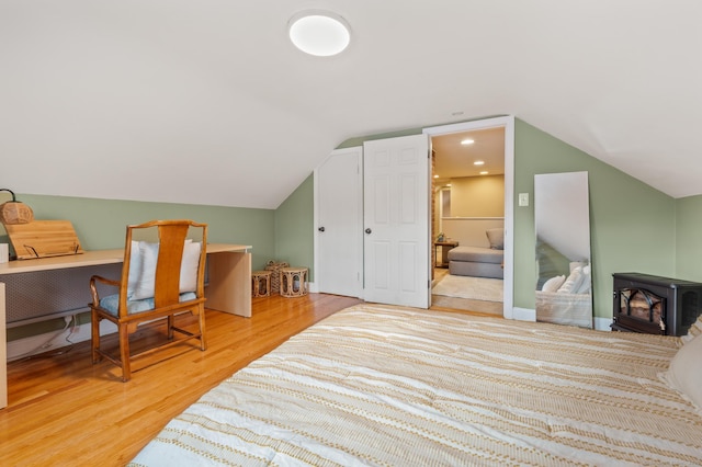 interior space with vaulted ceiling, a wood stove, and light hardwood / wood-style floors